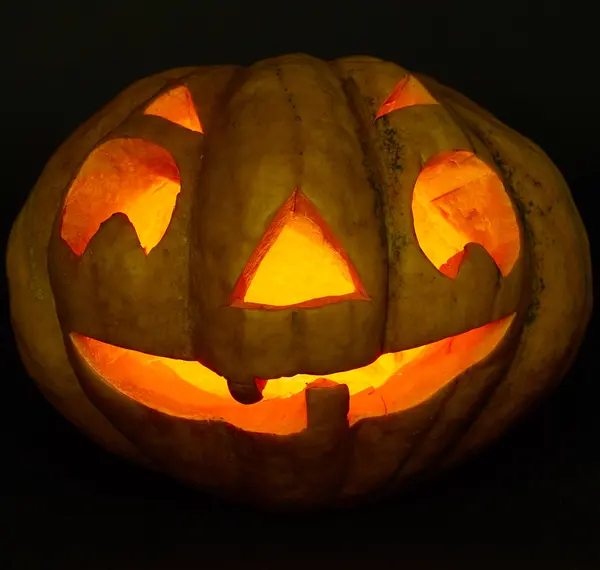 Cadılar Bayramı Balkabağı bir mum içinde. siyah arka plan üzerine