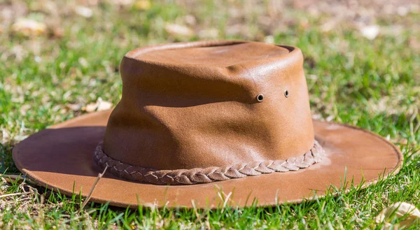 Um chapéu de cowboy marrom repousa na grama fresca em tempo ensolarado — Fotografia de Stock