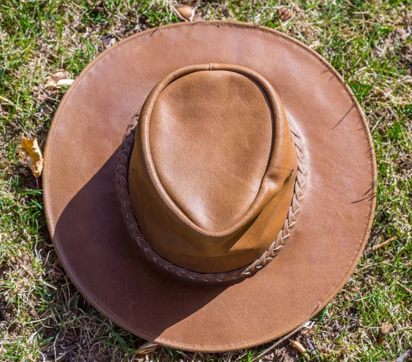 Güneşli havalarda taze çimenlerin üzerinde kahverengi kovboy şapkası aittir — Stok fotoğraf