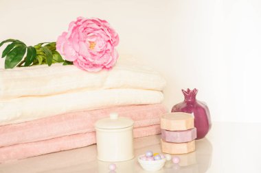 Beyaz ve pembe renklerde banyo ayarı. Havlu, aroma yağı, çiçek, sabun. Seçici odak, yatay.