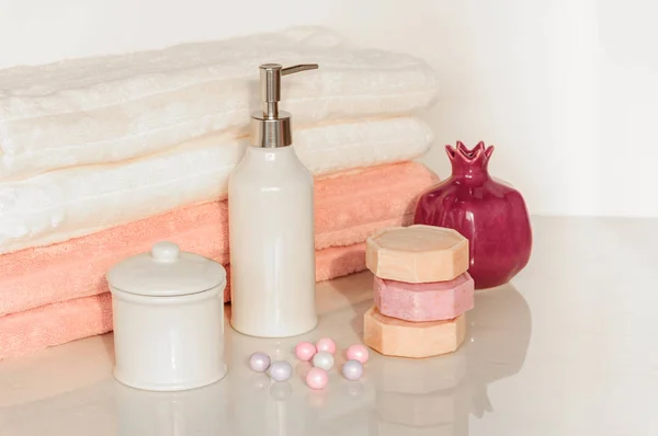 Réglage de bain dans des couleurs blanches et roses. Serviette, huile aromatique, fleurs, savon. Concentration sélective, horizontale . — Photo