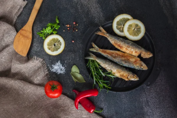 Usmażyć sardynki. pieczeń, broi, ryby-gril na patelni żeliwnych z warzywami i przyprawami wokół — Zdjęcie stockowe