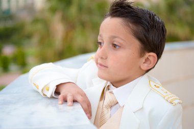 Young First Communion boy leaning on a wall clipart