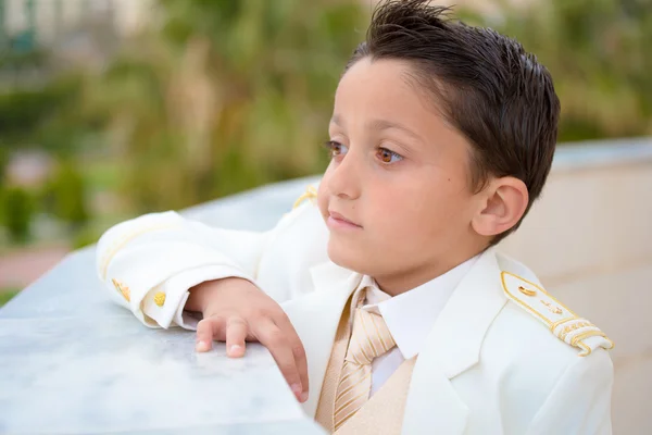 Jeune garçon première communion appuyé sur un mur — Photo