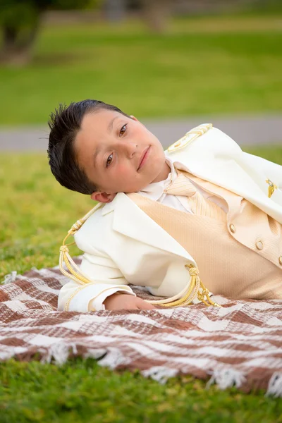 Young eerste communie jongen liggend op een deken in de buitenlucht — Stockfoto