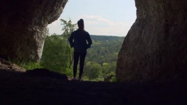 Kayalık Mağarada Duran Kadın - Arka planda Ormanlı Siluet