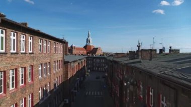 Arka planda antika kırmızı tuğla binalar ve tarihi kilise olan eski konutlar.