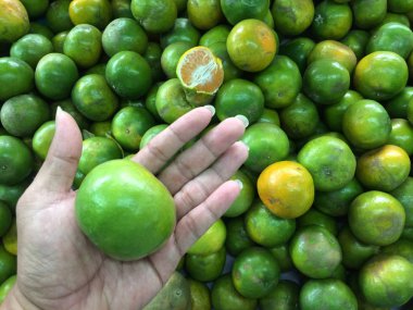 Genç adam bir mandalina elinde tutan.