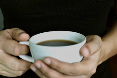 Kupası elinde tutan yakın çekim genç kadın. (sığ Dof; Renk tonlu görüntü)