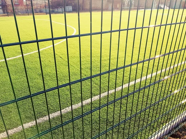 lawn field for playing minifootball behind the green fence mesh