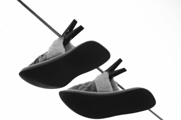 A pair of home slippers are dried on a clothesline with clothespins, bw. — Stock Photo, Image