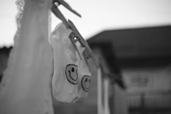 Chaussettes et autres vêtements sont séchés sur une corde avec des pinces à linge, cour avec des bâtiments, belle mise au point sélective, bw . — Photo