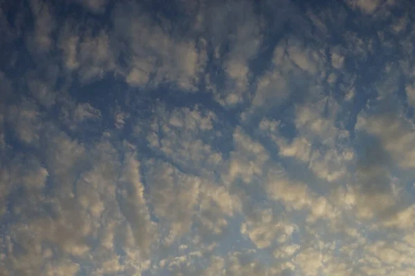 Abend blauer Himmel mit weißen, goldenen Wolken. — Stockfoto