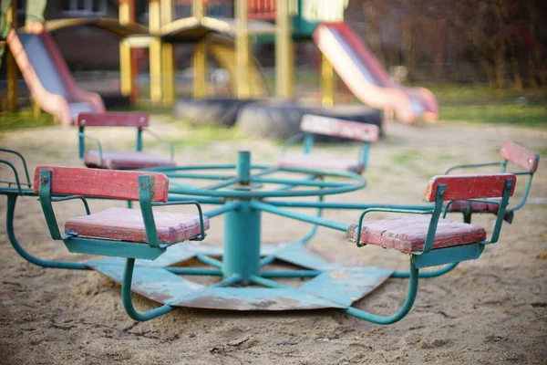 Parque infantil com um velho carrossel na areia . — Fotografia de Stock