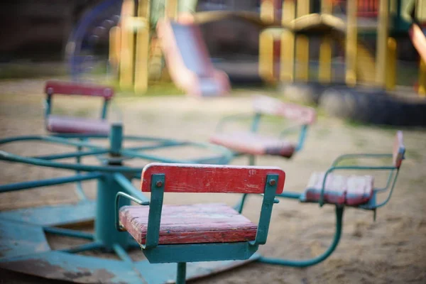 Zona de juegos con un viejo carrusel en el primer plano de arena . — Foto de Stock