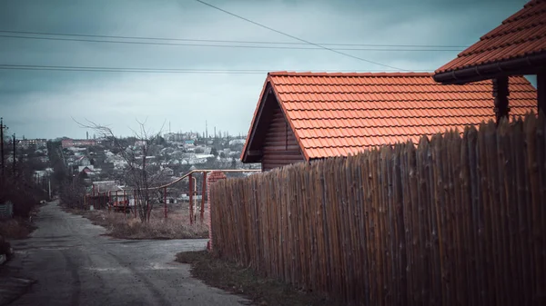 Strada rurală. Gard din mize de lemn ascuţite. Casă cu acoperiș cu gresie roșie — Fotografie, imagine de stoc