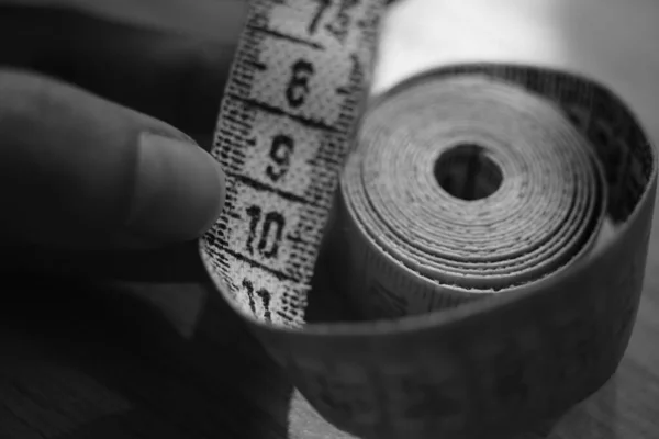 Measuring tape on the human fingers. Black and white photo. — Stock Photo, Image