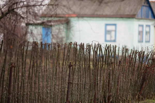 Vechi gard rural wattle gard din tije de lemn pe fundalul casei — Fotografie, imagine de stoc