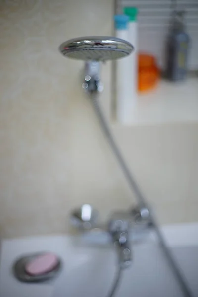 Shower hose and faucet in the bathroom on the background of shampoo and shower gel. Unfocused. — Stock Photo, Image