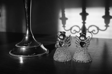 İki küçük melek heykeli klasik şamdanın yanında. Siyah beyaz fotoğraf.