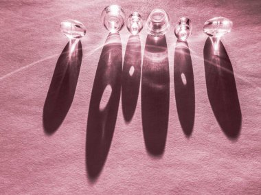 Pembe bir masanın üzerinde yuvarlak cam düğmeler, sert ışık ve gölge..