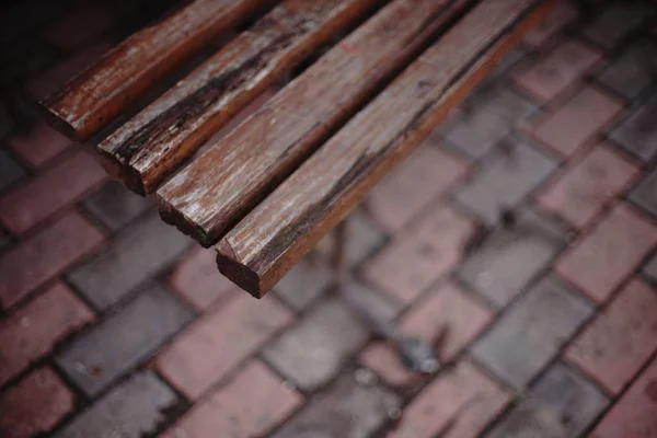 Старая деревянная скамейка с пилинговой краской, вид сверху, размытый пол с плиткой . — стоковое фото