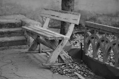 Taş çitin yanında boyası soyulan eski ahşap bir bank..