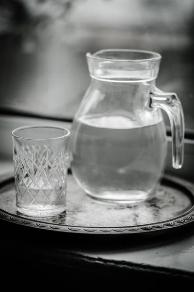 Tasse d'eau et un verre sur le rebord de la fenêtre, photo noir et blanc . — Photo