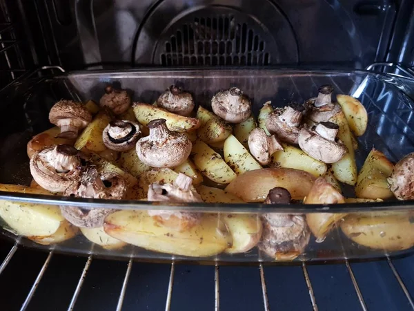 Pommes de terre tranchées chaudes prêtes et champignons entiers cuits au four, le processus de cuisson est terminé . — Photo