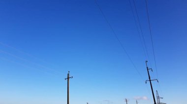 Mavi gökyüzü arka planında iki sıra enerji hattı
