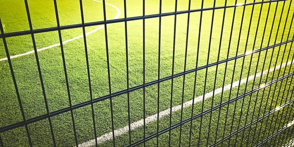 Sonniger Rasenplatz zum Spielen von Minifußball hinter dem grünen Zaun Gitter, Sport Hintergrund. — Stockfoto