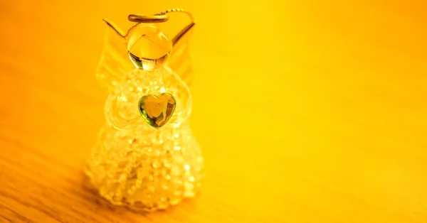 Little angel figurine with a heart on the table, golden light. — Stock Photo, Image