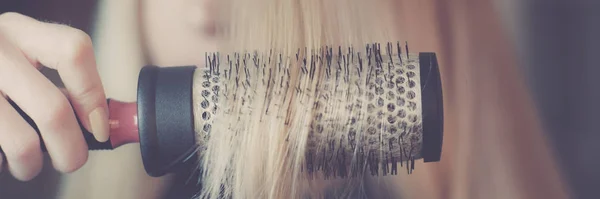 Round brushing in hand combs long blond hair closeup. — Stock Photo, Image