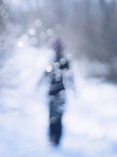 Loop door het winterbos. Silhouet van een eenzaam persoon in het zwart lopend op de weg. — Stockfoto