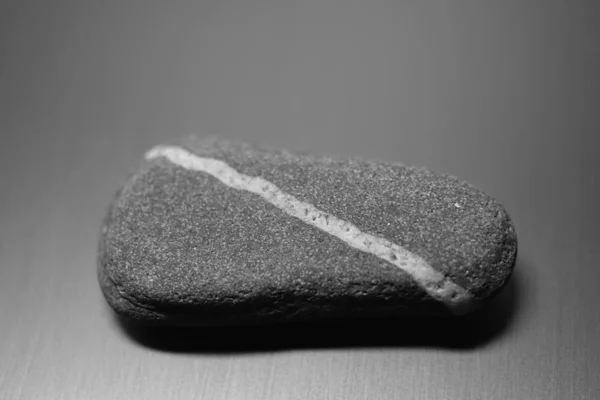 Pedra de seixo com linha branca diagonal natural sobre a mesa, bw foto . — Fotografia de Stock