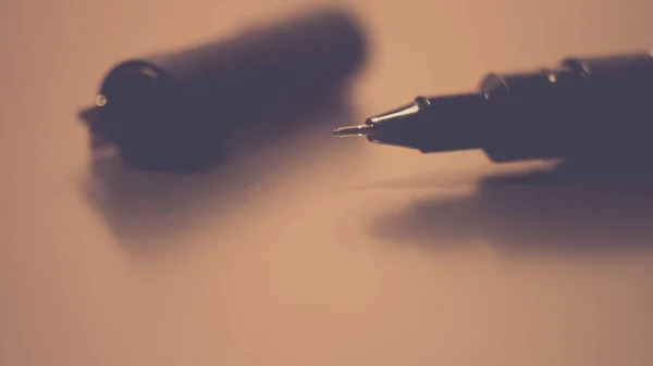 Caneta preta em um papel de caderno branco, acessório para criatividade na mesa . — Fotografia de Stock