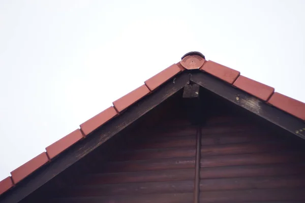 Parte del frontone di una casa in legno con una tegola di metallo rosso sul tetto . — Foto Stock