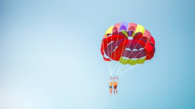 Gökyüzündeki iki paraşütçü mutlu bir paraşütün altında uçuyor..