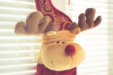 Boynuzlu geyik, yumuşak oyuncak, yeni yıl arifesinde, jaluzi ile pencereye as..