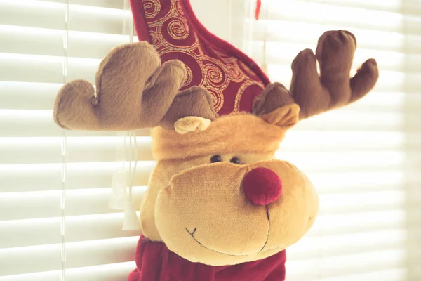 Олень с рогами, мягкая игрушка, висит на окне с жалюзи, канун Нового года . — стоковое фото