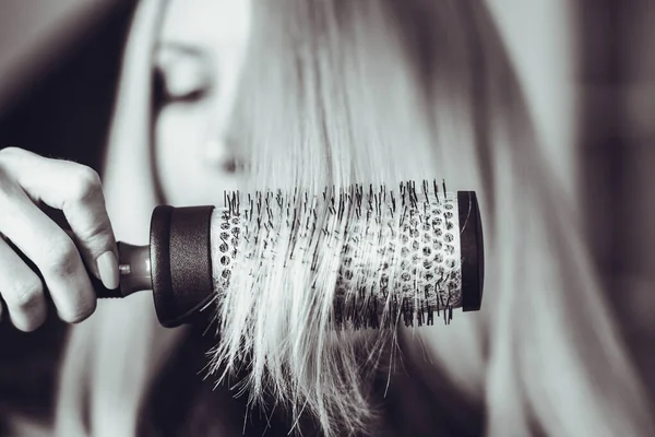 Comb round hairbrush long hair, in the background the blurry face of a girl, bw photo. — Stock Photo, Image