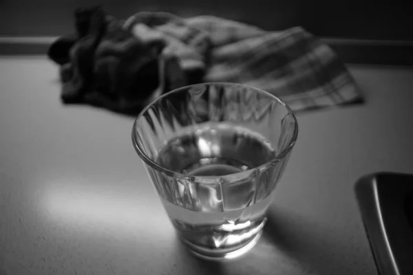 Metade de copo de água em um close-up de mesa, foto em preto e branco . — Fotografia de Stock