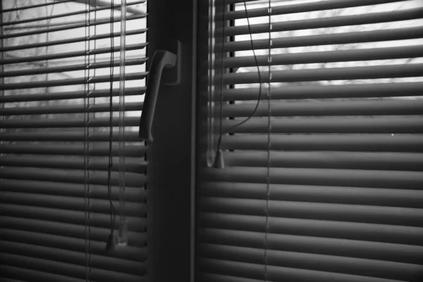 Окно с полузакрытыми жалюзи в темной комнате. Джалоузи. Черно-белое фото . — стоковое фото
