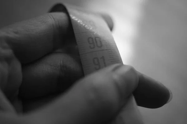 Measuring tape on the female fingers. Black and white photo. — Stock Photo, Image