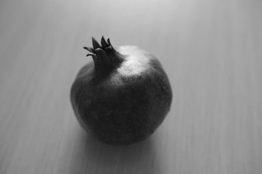 Tahta güneşli masada olgun bir nar, bw.