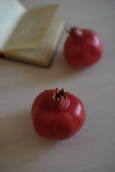 Two whole ripe pomegranate and an open recipe book — Stock Photo, Image