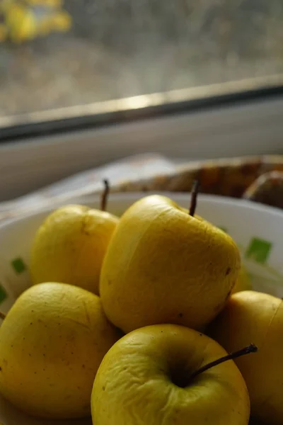 Régi természetes sárga alma egy tányéron egy ablakpárkányon. — Stock Fotó