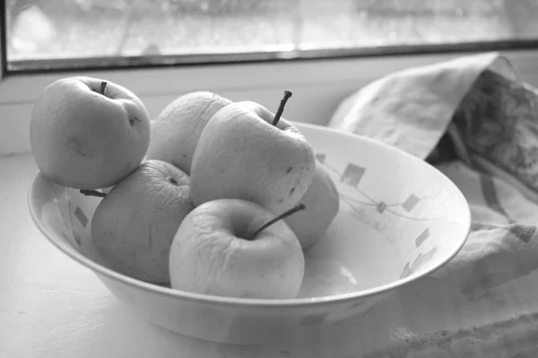 Natural apples in a plate on a windowsill, bw — Stock Photo, Image