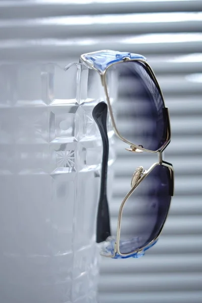 Stylish sunglasses hang on a crystall vase closeup. — Stock Photo, Image