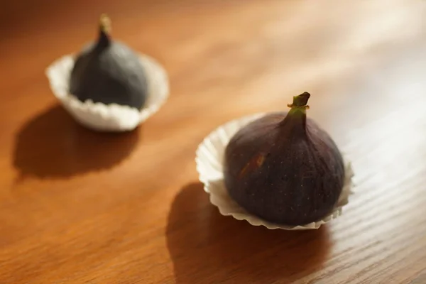 Dois figos doces maduros em papel branco em uma mesa de madeira . — Fotografia de Stock